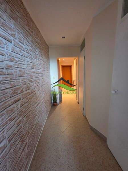 A hallway in a 3-room apartment with a stone decor on the wall and tiles on the floor.