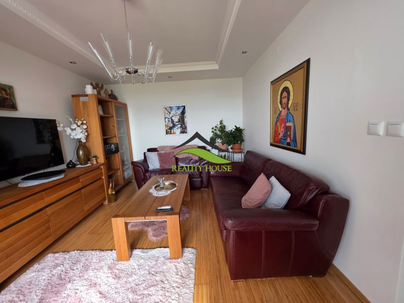 Living room with wood-patterned flooring, leather sofa, and an icon in a 3-room apartment.