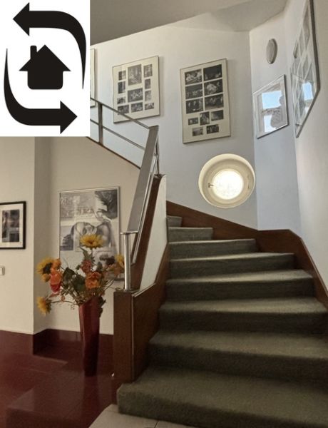 The staircase of the villa with a carpet, flower decorations, and artistic frames on the walls.