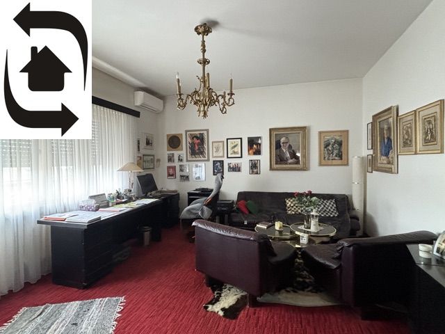 Living room in a villa with a red carpet, sofa, and paintings on the walls.