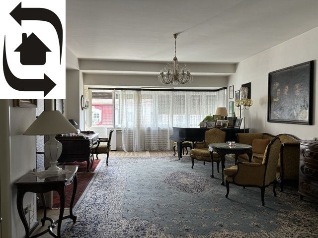 Living room of the villa with a Persian carpet, piano, and large windows.