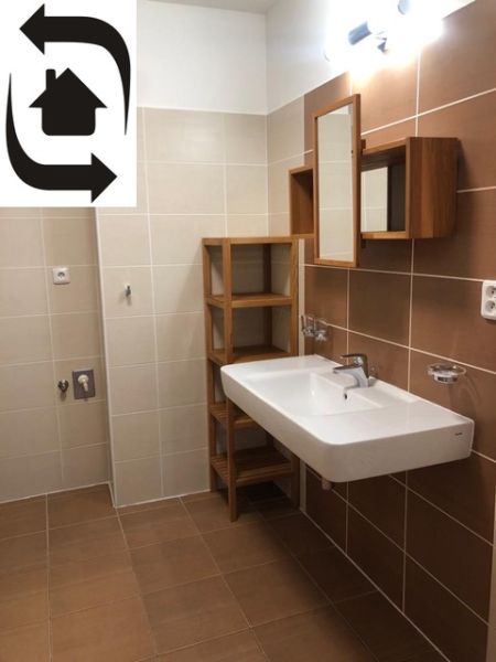Bathroom in a 2-room apartment with brown tiles and a white sink.