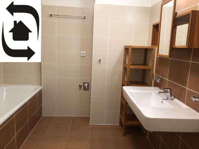 A bathroom in a 2-room apartment with light tiles, a bathtub, and a sink.