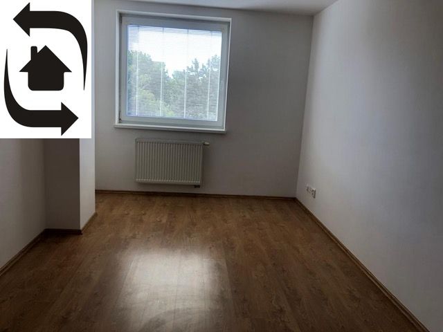 A room in a 2-room apartment with a wood-patterned floor and a window with a view.