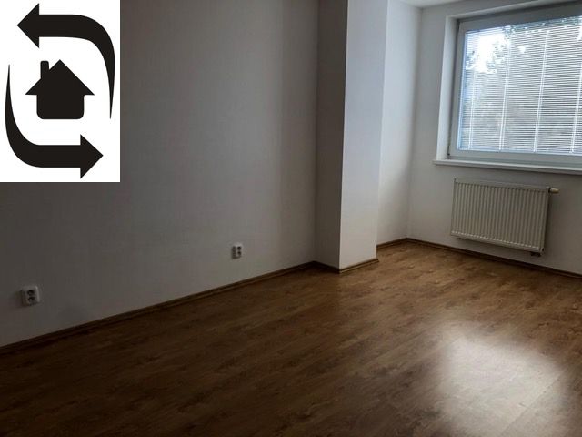 Empty room with wood-patterned flooring and a large window in a two-room apartment.