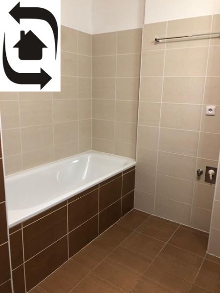 A bathroom in a 2-room apartment with a bathtub and beige tiles.