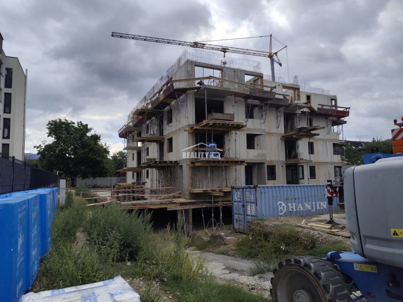 Construction of a residential complex in Beluša with an unfinished 3-room apartment and a construction crane.