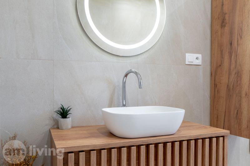 A bathroom in a family house with a wooden decor floor and a round mirror.