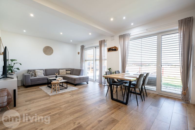 Living room with wood-patterned flooring, large sofa, and dining table in a family house.