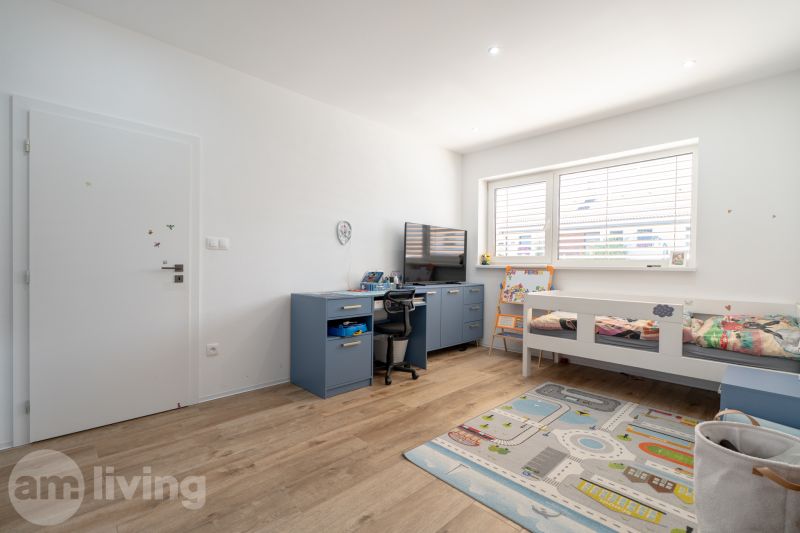 Children's room in a family house with a bed, table, and floor with a wooden decor.