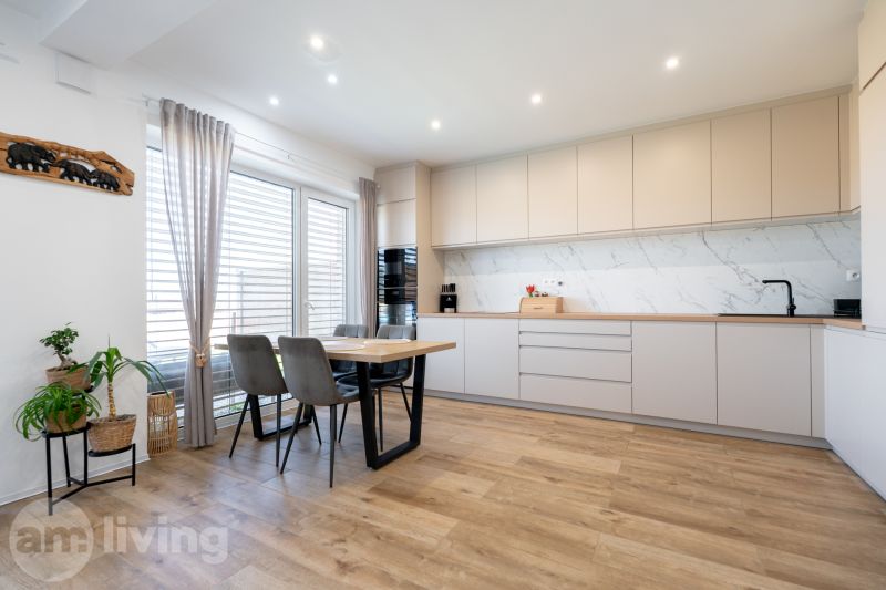 A bright kitchen of a family house with a wooden decor floor and a dining table.
