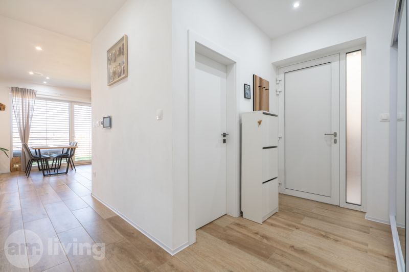 Entrance hallway of a family house with a wooden decor floor and a well-lit dining room.