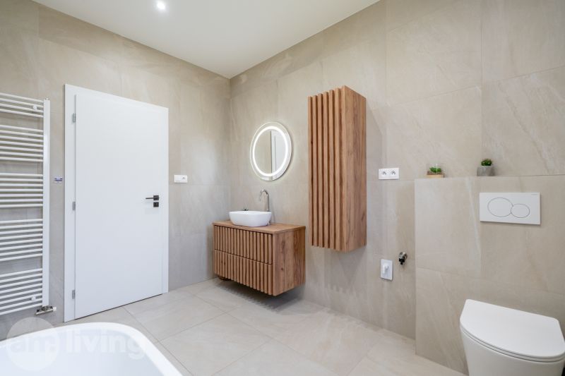 A bathroom in a family house with wooden decor and a round mirror.