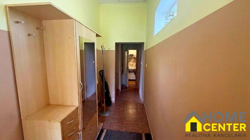A hallway in a cottage with wooden decor furniture and a coat rack.
