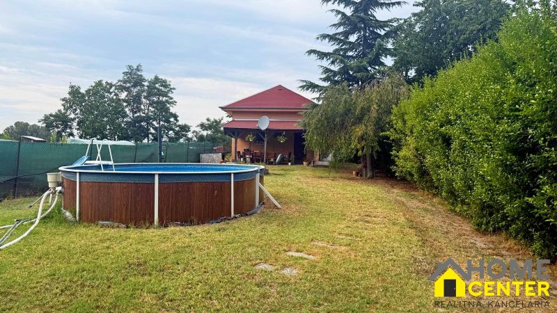 The exterior of the cottage in Komárno with a pool and a garden full of greenery.