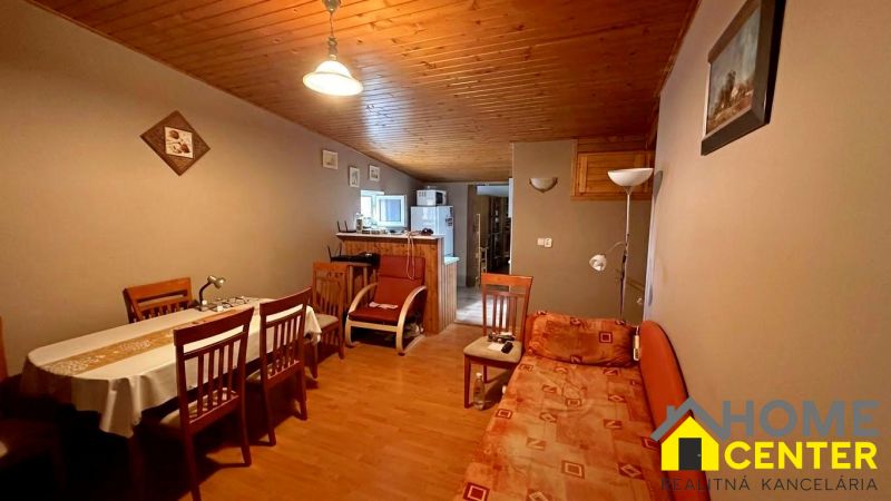 The interior of a cabin with a wooden ceiling, a floor with a wooden decor, and a dining table.