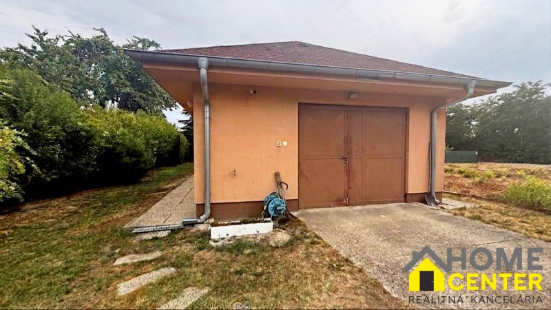 The exterior of the cottage in Komárno with a garage surrounded by a lawn.