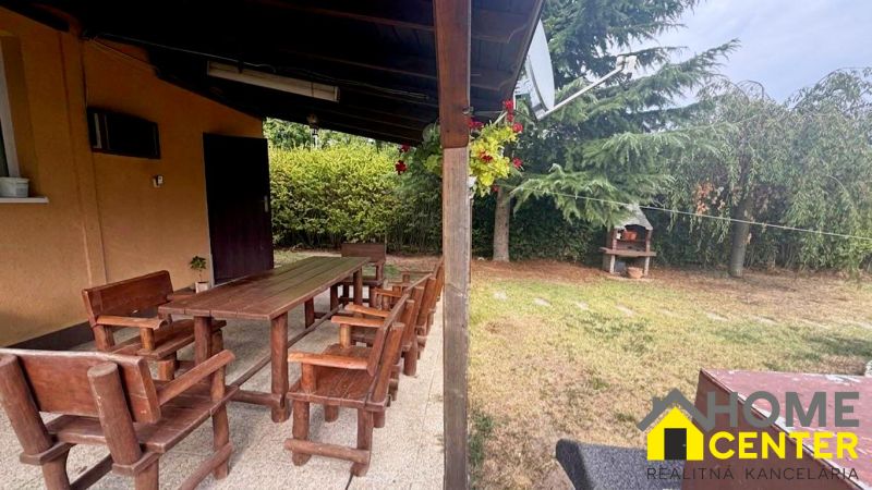 A covered terrace at the cottage in Komárno with seating and a garden grill.
