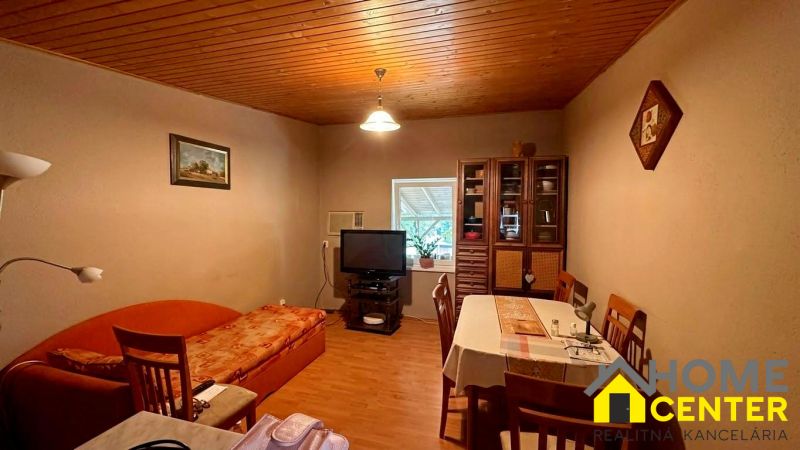 Living room in a cottage with a kitchen table, sofa, and wooden decor flooring.