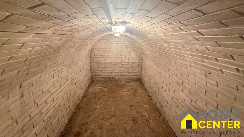 A brick-walled cellar in a cottage with an undecorated floor.