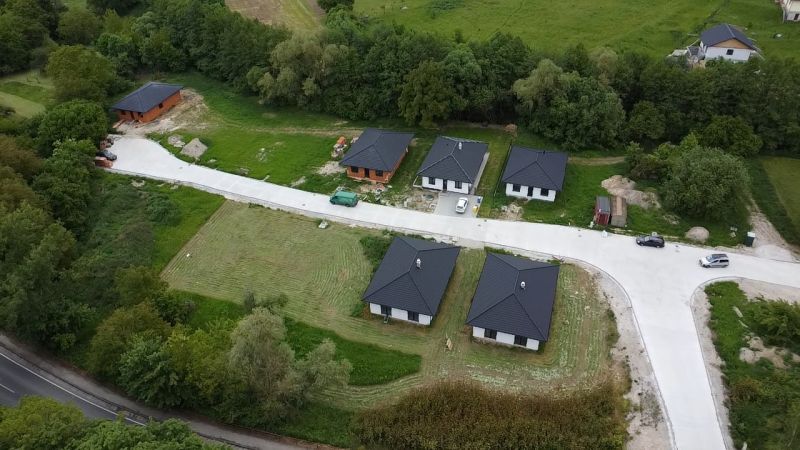 Aerial view of six family houses in Prašník surrounded by greenery and an access road.