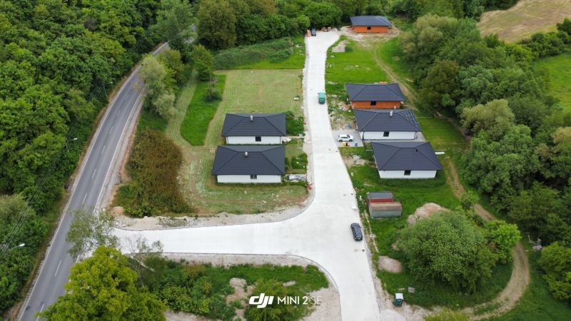 Family houses in the village of Prašník surrounded by greenery and an access road.