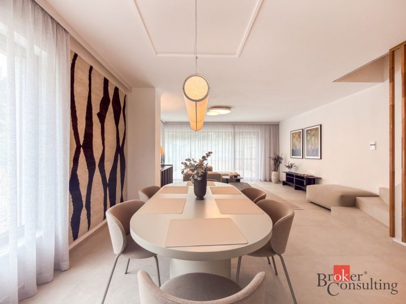Dining room in a 4-room apartment with large windows and a decorative carpet on the wall.
