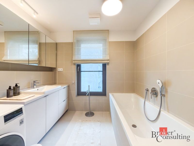 A bathroom in a 4-room apartment with a bathtub, sink, and washing machine.