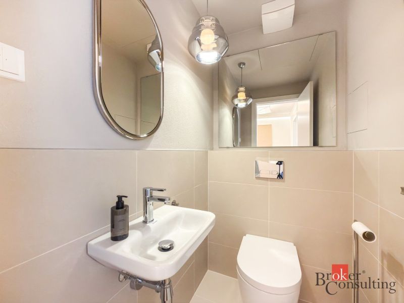 A bathroom with a mirror, sink, and toilet in a 4-room apartment.