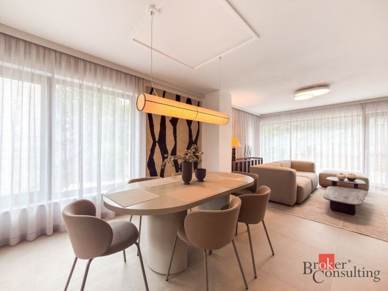 Dining area with a large table in a 4-room apartment, seating by the windows with curtains.