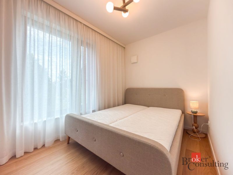Bright bedroom with wood-patterned flooring and a large window in a 4-room apartment.
