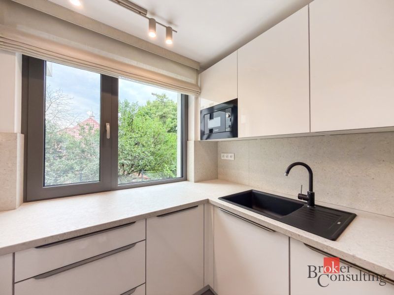 A kitchen in a 4-room apartment, with white cabinets and a black sink.