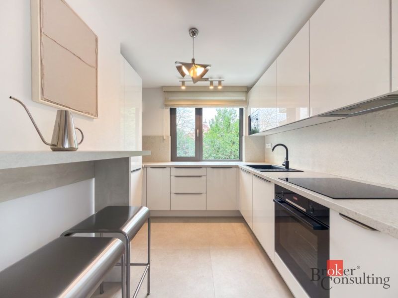 A bright kitchen with built-in appliances in a 4-room apartment with a wooden decor floor.