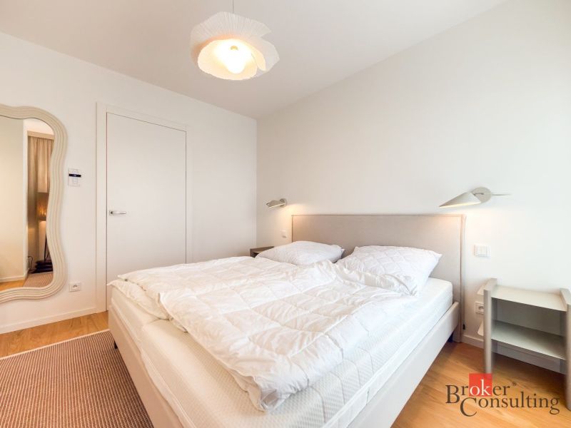 A bedroom in a 4-room apartment with an upholstered bed and a wooden decor floor.