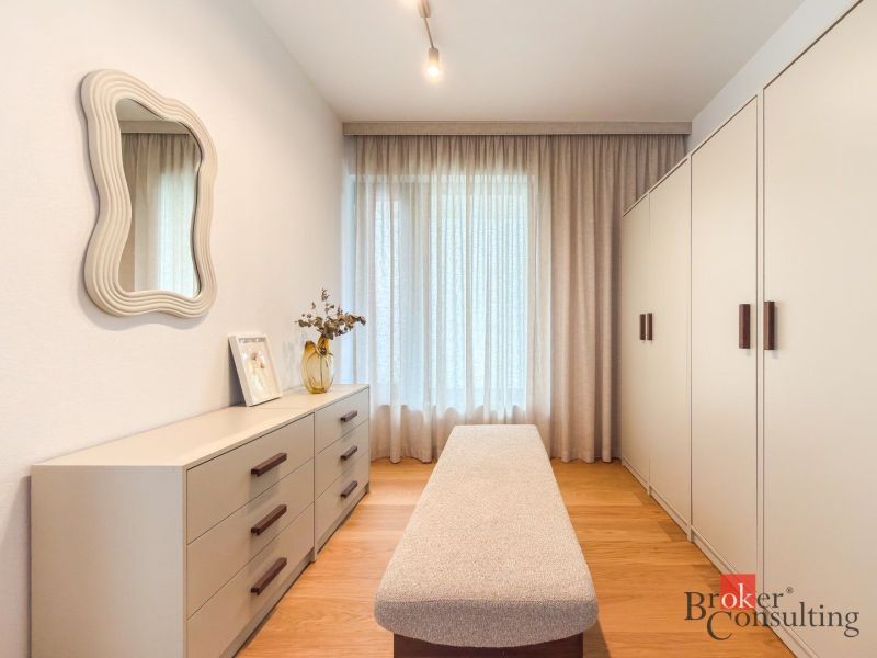 A wardrobe with a mirror, a closet, and a dresser in a 4-room apartment with a wooden decor floor.