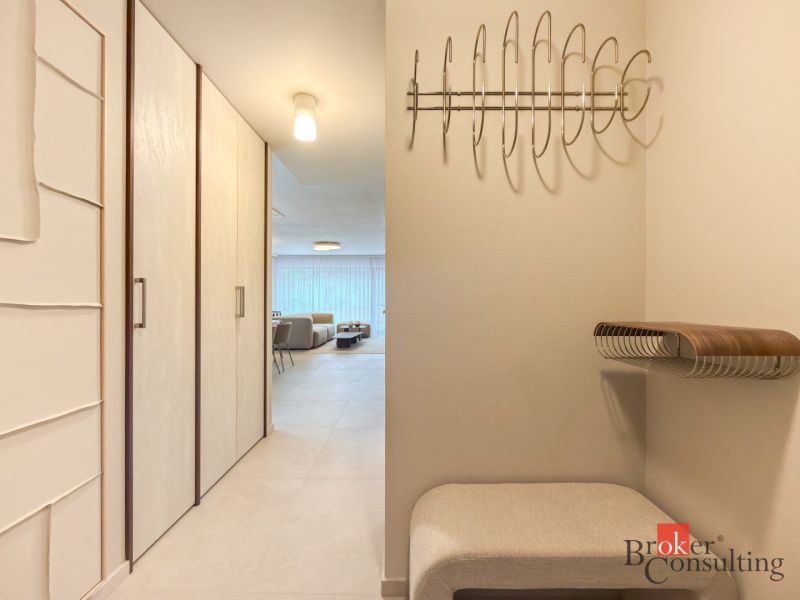 Entrance hall with a wardrobe, hangers, and a sofa in a 4-room apartment.