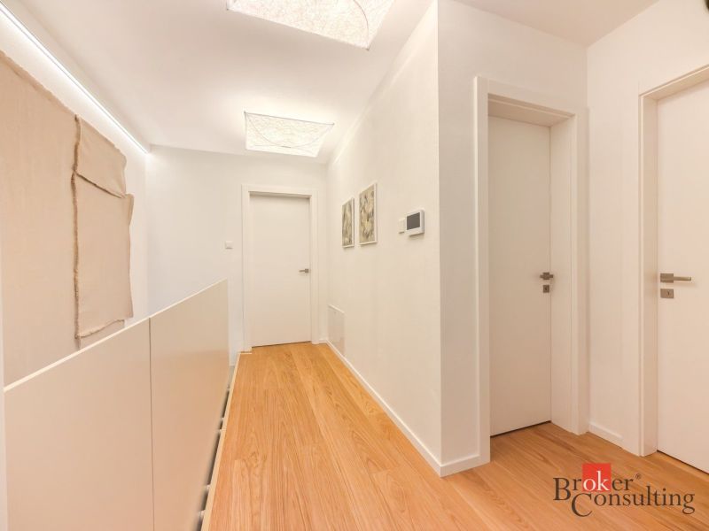 A corridor with a wooden decor floor in a 4-room apartment, white doors and walls.