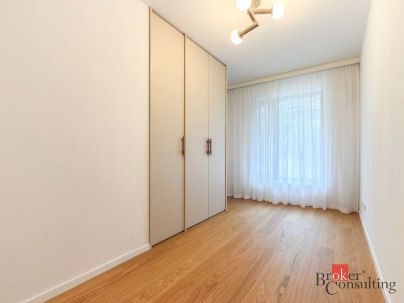 A room with a wooden decor floor, wardrobes, and curtains in a 4-room apartment.
