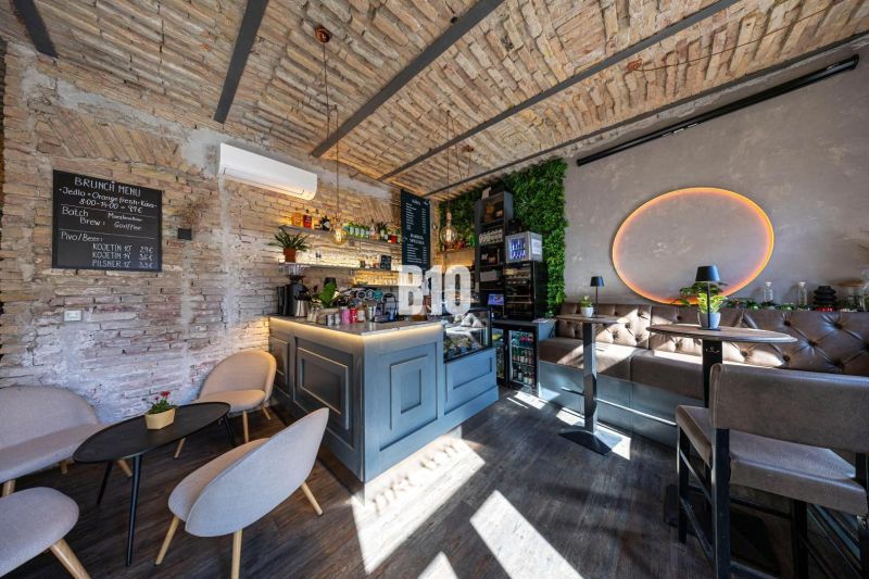 Interior of a gastro space with a bar counter, brick walls, and a wooden decor floor.