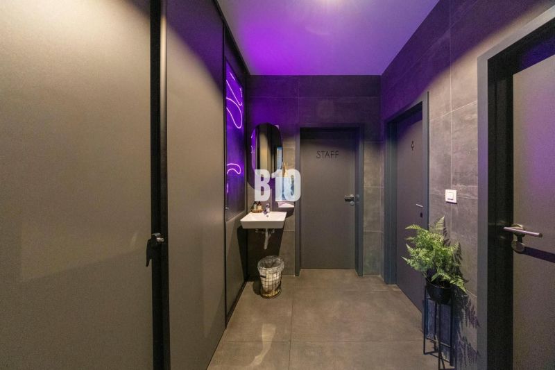 Interior of a gastro space with purple lighting, a sink, and subtle decorations.