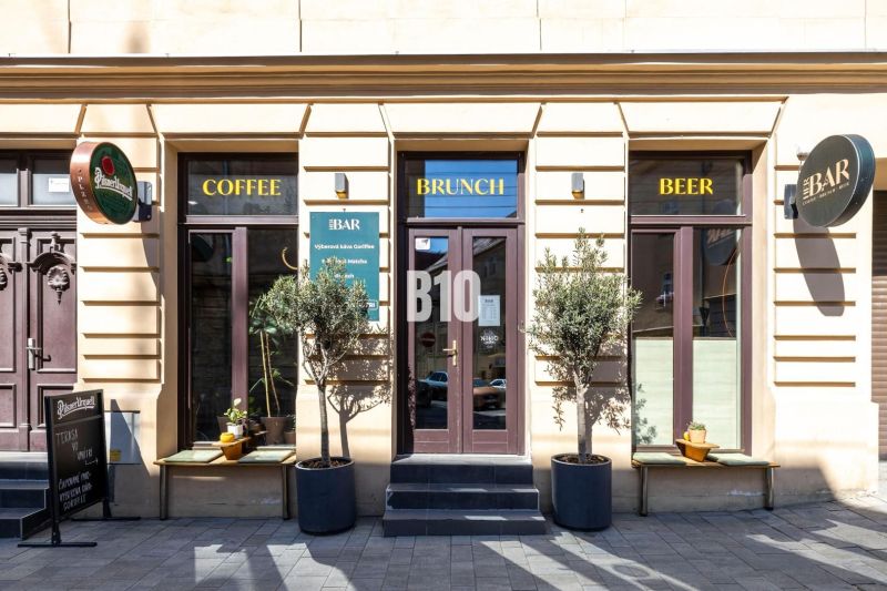 The exterior of a café and bar in Bratislava - Old Town with three entrances and signs.