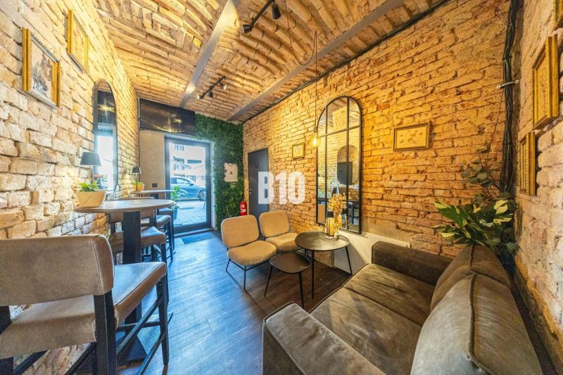 Interior of a gastro space with brick walls, comfortable seating, and a wooden-patterned floor.