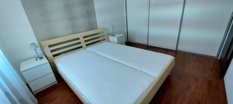 A bedroom in a 3-room apartment with a wood-patterned floor, white furniture, and lamps.