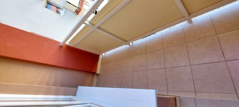 A covered balcony of a 3-room apartment with a tiled floor.