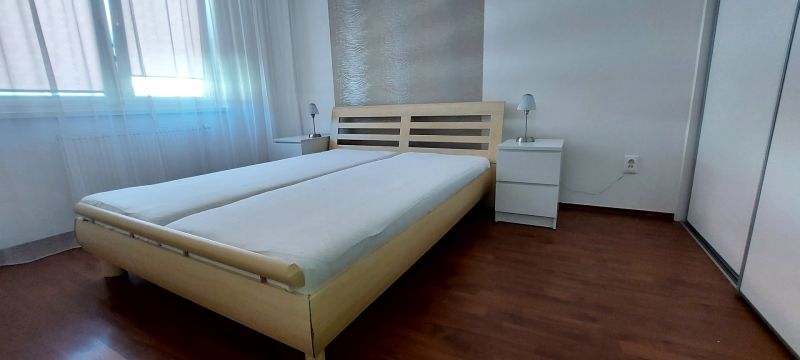 Bedroom with a bed and nightstands, wooden decor flooring in a 3-room apartment.