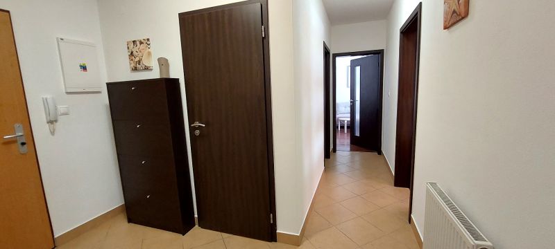 A hallway with entrance doors, room doors, and tiles in a 3-room apartment.