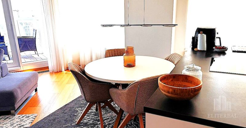 Dining area in a 3-room apartment with a wood-patterned floor and a round table.