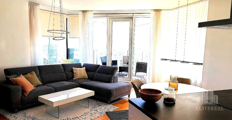 Living room of a three-room apartment with a corner sofa and a table, floor with a wooden decor.