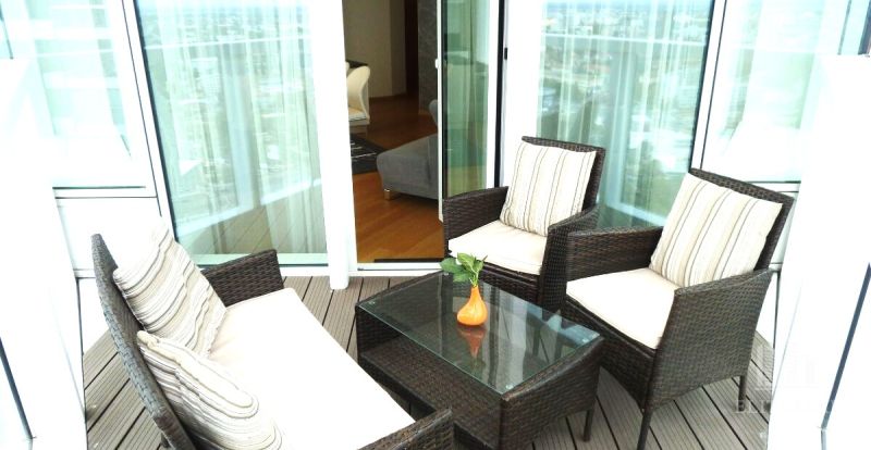 A balcony with wicker furniture and a glass table in a 3-room apartment.