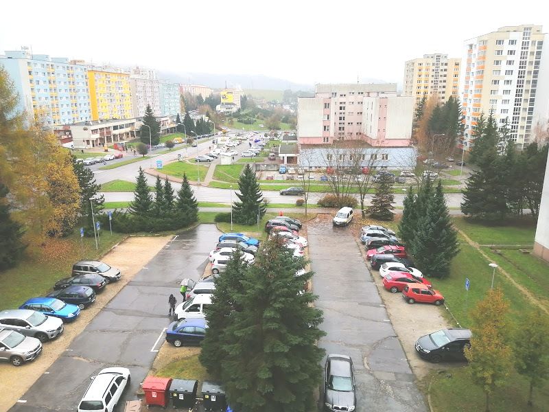 View from a 3-room apartment on Krivánska Street in Banská Bystrica with a parking lot and panel buildings.